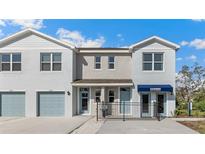 Modern townhome exterior featuring light gray stucco, blue doors, and a well-manicured lawn at 4605 Pleasant Ave, Palm Harbor, FL 34683