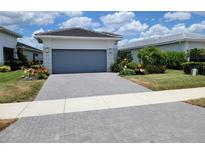 Charming home featuring a paved driveway leading up to a garage with gray door, surrounded by lush landscaping at 5219 Barnett Cir, Bradenton, FL 34211