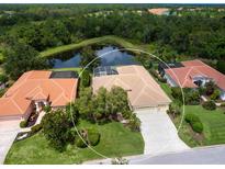 Stunning aerial view of a well-maintained home with a tile roof, lush landscaping, and a serene water view at 6811 Honeysuckle Trl, Lakewood Ranch, FL 34202
