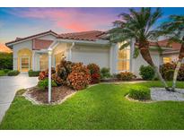 Charming single-story home featuring a red tile roof, lush landscaping, and well-manicured lawn at 8382 Creekview Ln, Englewood, FL 34224