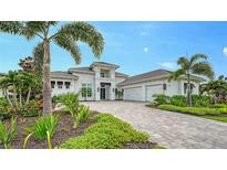 Stunning white home with a paver driveway, lush landscaping, and palm trees at 8537 Pavia Way, Bradenton, FL 34202