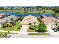 Inviting single-story home featuring a tile roof, manicured landscaping, and serene water views in a golf community at 8772 Stone Harbour Loop, Bradenton, FL 34212