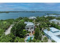 Stunning aerial view of coastal home with pool and lush landscaping, nestled near the bay at 8963 Fishermens Bay Dr, Sarasota, FL 34231