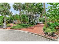 Stately three-story home featuring lush tropical landscaping and a red brick circular driveway at 8963 Fishermens Bay Dr, Sarasota, FL 34231