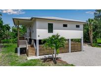 Stunning elevated home featuring a modern design, a wooden fence and staircase and a well-manicured lawn at 105 Shore Rd, Nokomis, FL 34275