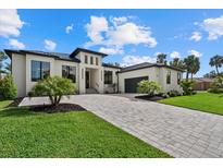 Contemporary home showcasing a paved driveway, lush lawn, and modern architectural details at 1605 Landfall Dr, Nokomis, FL 34275