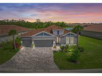 Charming single-story home with tile roof, manicured lawn, and brick paver driveway at 460 Daylily Blvd, Nokomis, FL 34275