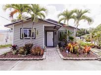 Charming home with lush landscaping, a brick walkway, and tropical palm trees at 4945 Camphor Ave, Sarasota, FL 34231