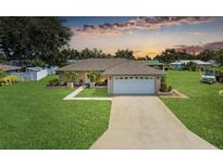 Charming single-story home with a well-manicured lawn, concrete driveway, and a two-car garage under a cloudy sunset sky at 6804 19Th W Ave, Bradenton, FL 34209