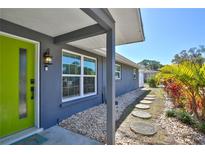 Inviting front entrance with lime-green door and stepping stones, showcasing the home's unique charm and landscaped appeal at 7355 Cass Cir, Sarasota, FL 34231