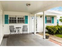 Charming covered front porch with teal shutters, seating area and a neutral color palette at 9412 Concord Cir, Bradenton, FL 34210