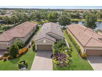 Stunning aerial view of the home with tile roof, brick driveway, and lush landscaping by the pond at 13338 Torresina Ter, Lakewood Ranch, FL 34211