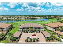 Exterior view of a multi-Gathering home overlooking a lake and golf course, with lush landscaping and ample parking at 13609 Messina Loop # 104, Bradenton, FL 34211