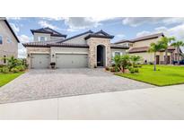 Stunning two-story home featuring a three-car garage, paver driveway, and beautifully landscaped front yard at 13871 Heartwood Way, Parrish, FL 34219