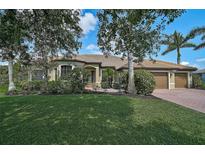 Beautiful single-story home with a well-manicured lawn, mature trees, and a charming red brick driveway at 306 Country Meadows Way, Bradenton, FL 34212