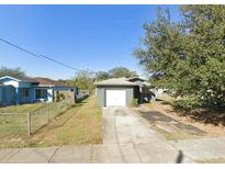 View of the home's exterior and front yard featuring a driveway leading up to a one-car garage and landscaping at 3622 N 51St St, Tampa, FL 33619