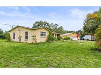 Charming yellow home with a well-maintained lawn and separate garage, creating a welcoming curb appeal at 5981 Jim Davis Rd, Parrish, FL 34219