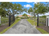 A gated entry leads to a large home with mature trees and manicured landscaping at 7025 Saddle Creek Cir, Sarasota, FL 34241