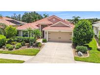 Charming single-story home featuring a red tile roof, a two-car garage, and lush landscaping in a well-maintained yard at 8906 Stone Harbour Loop, Bradenton, FL 34212