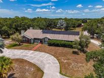 Charming single-story home with a brick-paved walkway, solar panels, and a circular driveway at 15440 County Road 675, Parrish, FL 34219