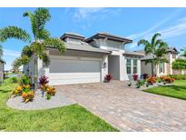 Beautiful single-Gathering home featuring lush landscaping, a paver driveway, and a two-car garage at 17333 Savory Mist Cir, Bradenton, FL 34211
