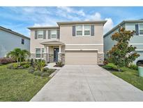 Two-story home featuring a two-car garage, stone accents, a lush lawn and manicured landscaping at 2136 Midnight Pearl Dr, Sarasota, FL 34240