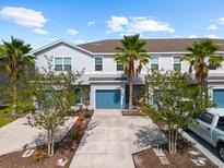 Charming townhouse with well-maintained landscaping, blue garage door, and palm trees in a sunny neighborhood at 4644 Vignette Way, Sarasota, FL 34240