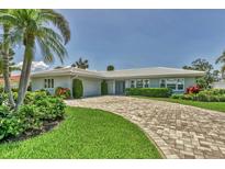 Beautiful home exterior features a brick driveway, lush landscaping, and well-manicured lawn at 510 Wedge Ln, Longboat Key, FL 34228
