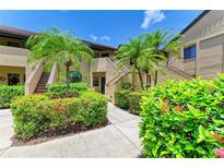 Inviting condo building with tropical landscaping, including palm trees and colorful flowering bushes at 5728 Ashton Lake Dr # 12, Sarasota, FL 34231