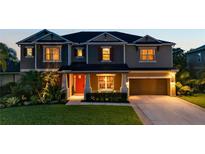 Inviting two-story home featuring a well-maintained lawn and a two-car garage, illuminated by warm exterior lighting at 6302 Anise Dr, Sarasota, FL 34238