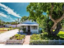 Charming single-story home with a white picket fence, lush landscaping, and a brick walkway leading to the front door at 717 84Th Nw St, Bradenton, FL 34209