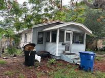 A quaint, light blue single-story home with a covered porch and a yard strewn with debris and garbage at 2230 50Th N Ave, St Petersburg, FL 33714