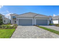 Beautiful home exterior with a two-car garage, paver driveway, and neatly manicured landscaping at 2321 Blue Mahoe Ln, Sarasota, FL 34240