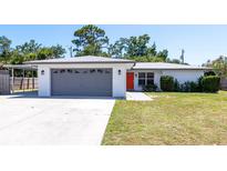 Charming single-story home featuring an attached garage, carport, and an inviting bright orange front door at 3338 Roslyn Rd, Venice, FL 34293