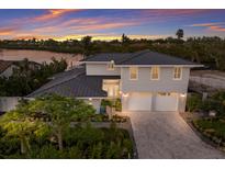 Stunning two-story home with a three-car garage, lush landscaping, and a beautiful sunset backdrop near the waterfront at 4 Winslow Pl, Longboat Key, FL 34228