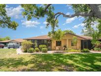 Charming single-story home featuring a screened patio with lush landscaping and mature trees on a sunny day at 4165 66Th Street W Cir # H, Bradenton, FL 34209