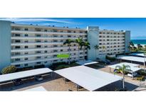 Multi-story condo building featuring covered parking and lush landscaping near the sandy beach at 5750 Midnight Pass Rd # 203, Sarasota, FL 34242