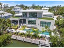Modern home with a pool, dock, and lush landscaping, perfect for waterfront living at 590 De Narvaez Dr, Longboat Key, FL 34228