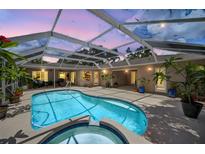 An enclosed backyard pool with a connected hot tub surrounded by lush plants and comfortable outdoor furniture at 6875 Myakka Valley Trl, Sarasota, FL 34241