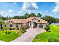 Stunning single-story home with well-manicured lawn and elegant brick-paved driveway leading to a two-car garage at 13503 22Nd E Ct, Parrish, FL 34219