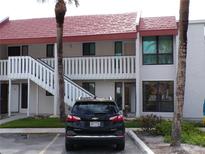 Charming condo building with red roof, white accents, and lush landscaping, creating an inviting curb appeal at 1801 Gulf N Dr # 207, Bradenton Beach, FL 34217