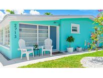Close up of a cozy turquoise home's entryway, featuring seating and manicured landscaping at 2713 Avenue C, Holmes Beach, FL 34217