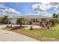 Charming single-story home with a tile roof, well-manicured lawn and circular driveway surrounded by tropical landscaping at 2807 Coral Way, Punta Gorda, FL 33950