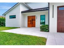 Contemporary home featuring a light-colored exterior and modern wood double-door entry at 289 Long Meadow Ln, Rotonda West, FL 33947