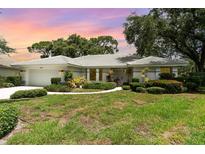 Charming single-story home boasts a tile roof, manicured lawn, and vibrant landscaping under a colorful sunset at 4353 Indian Point Trl, Sarasota, FL 34238