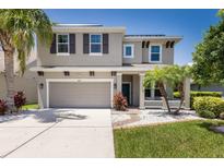 Charming two-story home featuring a well-manicured lawn, palm trees, and a two-car garage at 4617 Garden Arbor Way, Bradenton, FL 34203