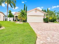 Charming single-story home features lush landscaping, a brick driveway, and a two-car garage under a bright blue sky at 4907 Kilty E Ct, Bradenton, FL 34203