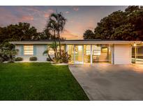 Charming single-story home with well-manicured lawn and an inviting screened-in front porch, complemented by lush landscaping at 5948 Mirror Lake Rd, Sarasota, FL 34238