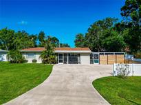 Charming single-story home with a well-manicured lawn and a long driveway leading to a screened in patio at 5948 Mirror Lake Rd, Sarasota, FL 34238