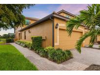Inviting home exterior featuring a two-car garage, lush landscaping, and a charming brick walkway at 6923 Grand Estuary Trl # 101, Bradenton, FL 34212